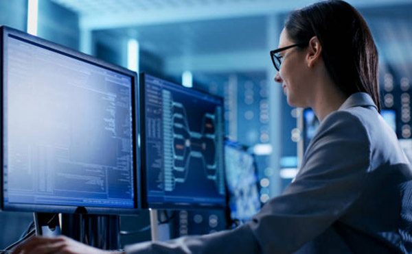 Close-up Shot of Female IT Engineer Working in Monitoring Room. She Works with Multiple Displays.